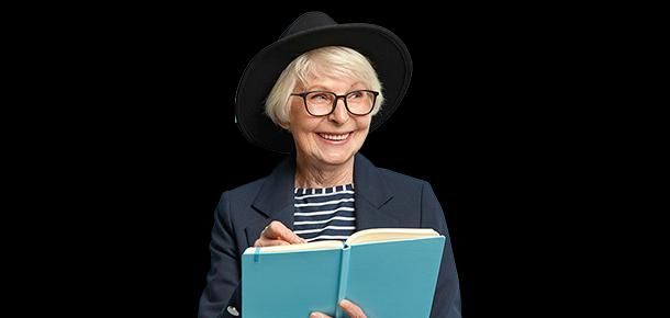 Uśmiechnięta seniorka w kapeluszu z otwartą książką w rękach.